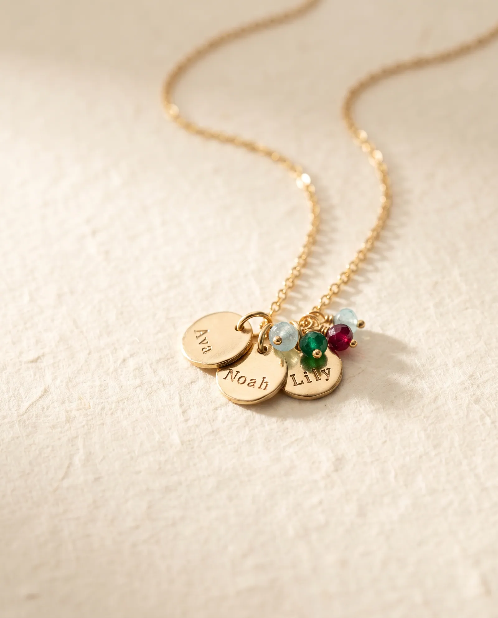Gold-tone necklace with three stamped name charms Ava, Noah and Lily with birthstone beads