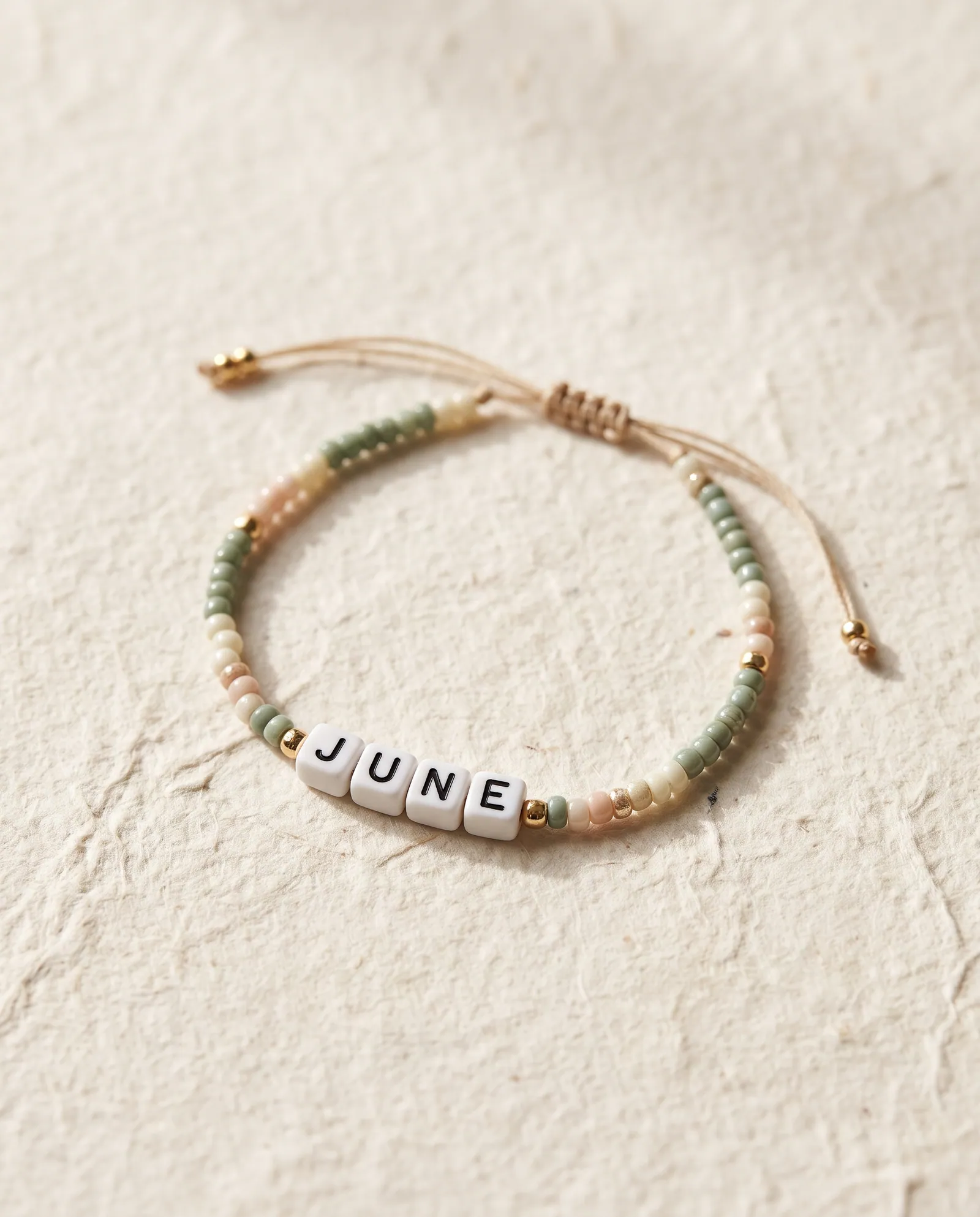 Beaded friendship bracelet in sage and cream with letter beads spelling JUNE